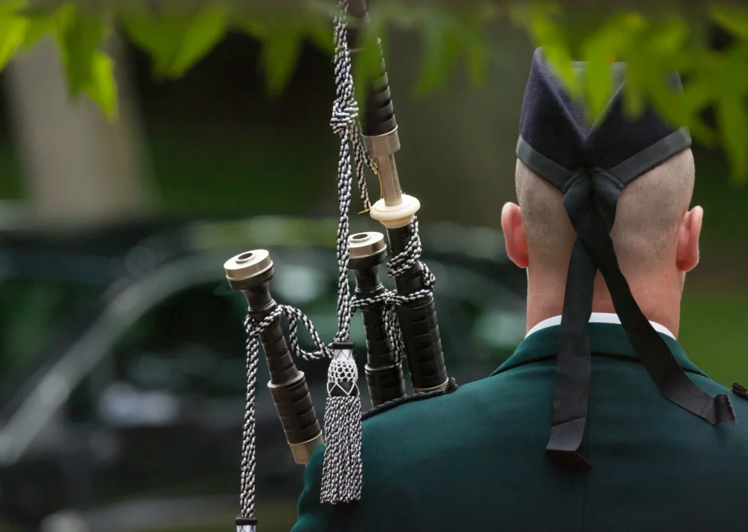 A Scottish piper at an outdoor funeral service.