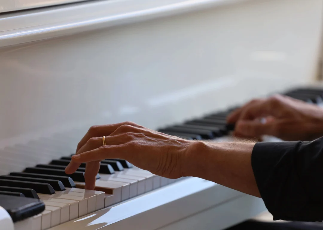 A woman's hands playing a white piano.