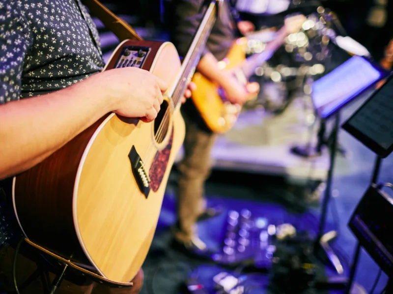A boy playing an acoustic guitar at a church concert.