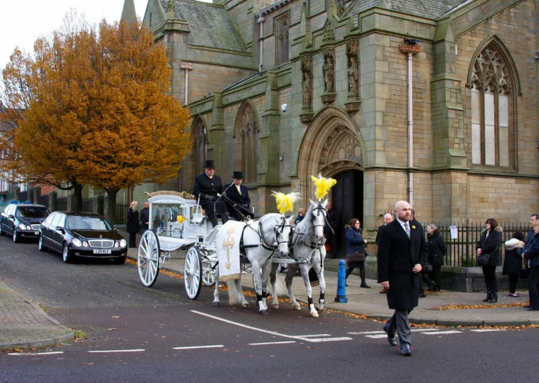 A white horse and carriage outside a church.
