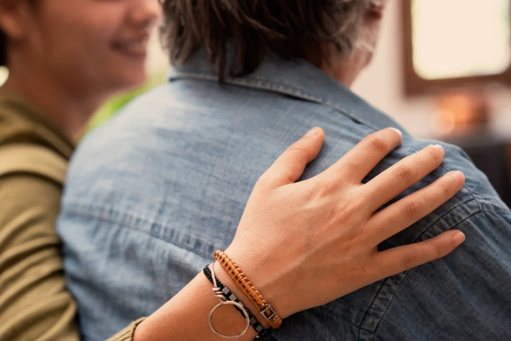 A daughter puts her arm around her dad's shoulder.