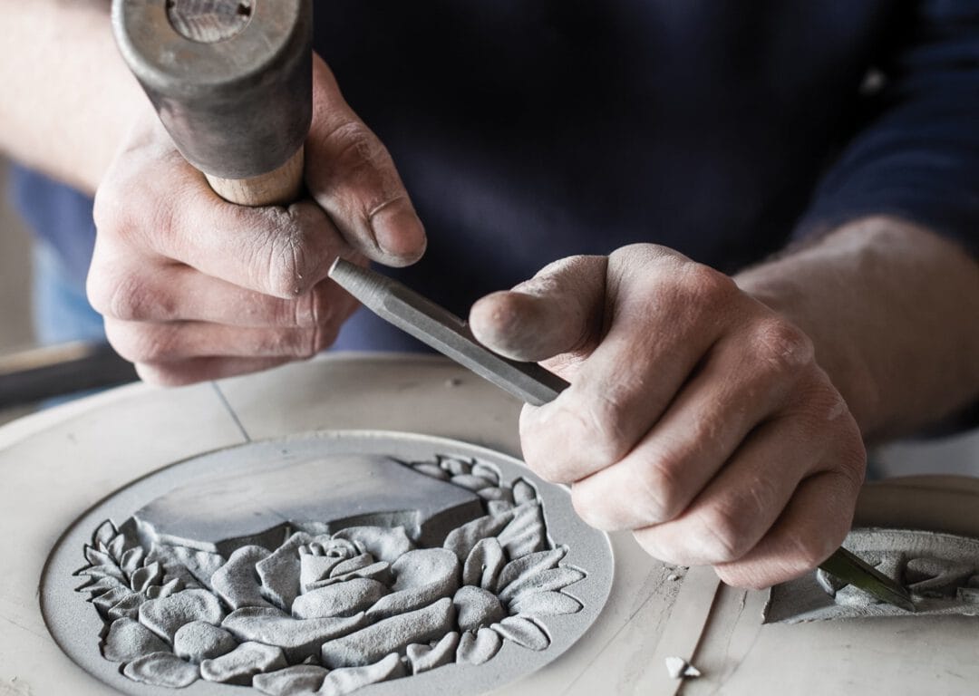 A man chiselling the surface of a headstone.